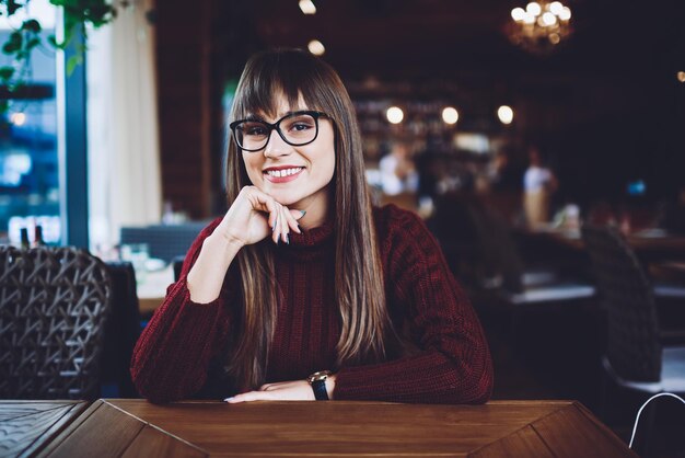 chica hipster sonriente con anteojos para corregir la visión mirando a la cámara con una linda sonrisa en la cara