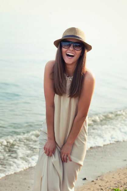 Chica hipster sonriente caminando en una playa de mar.