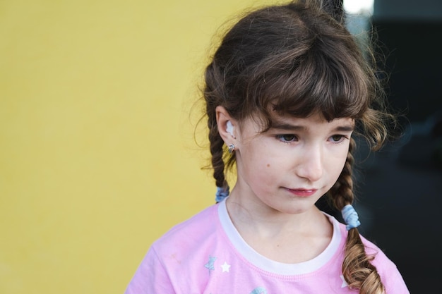 Chica con un hisopo de algodón terapéutico cálido en la oreja con una cara triste y llorosa sostiene su oreja Dolor de oído otitis media hinchazón de las encías dolor de muelas cirugía infantil otorrinolaringología