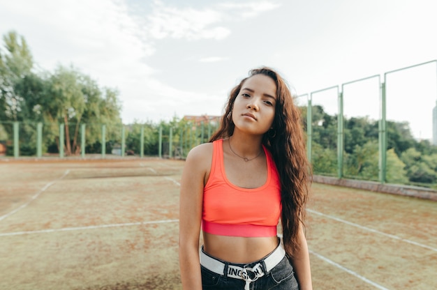 Chica hispana en una camiseta naranja posando