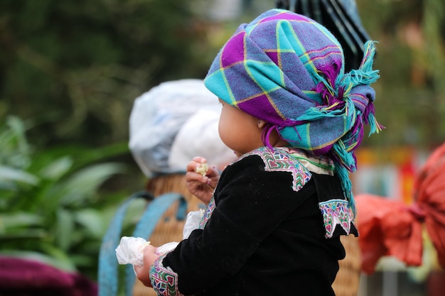 Foto chica hmong vestida con una colorida tela tejida a mano en la mano sosteniendo comida