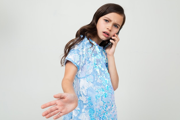 Chica honesta cuidadosamente hablando por teléfono en el interlocutor en un blanco