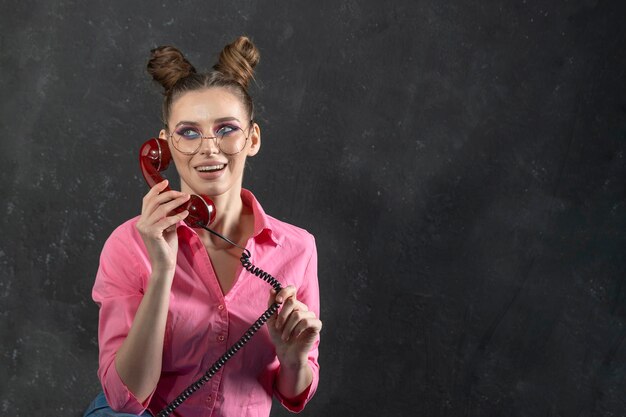 Foto chica en imagen interesante con conversaciones de maquillaje brillante en teléfono fijo retro sobre fondo negro en estudio espacio para texto