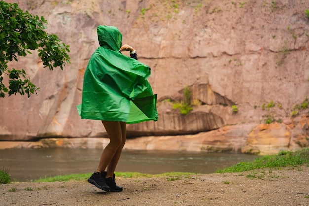 Una chica con un impermeable verde y una capucha al aire libre en la lluvia
