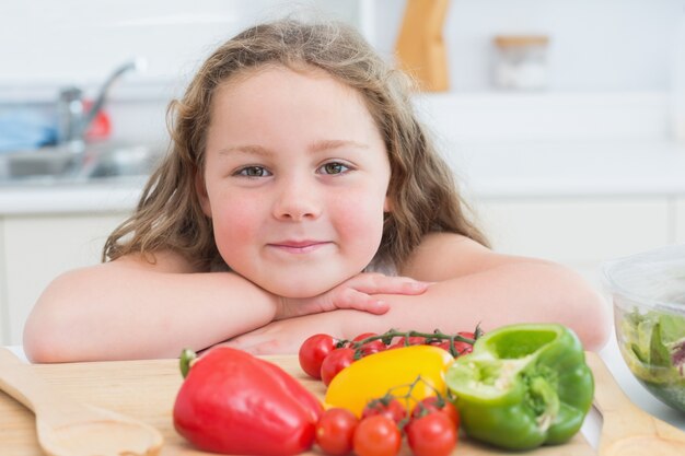 Chica inclinada al lado de verduras