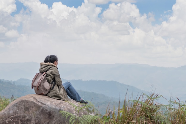 Chica inconformista sentada en rocosa de montaña