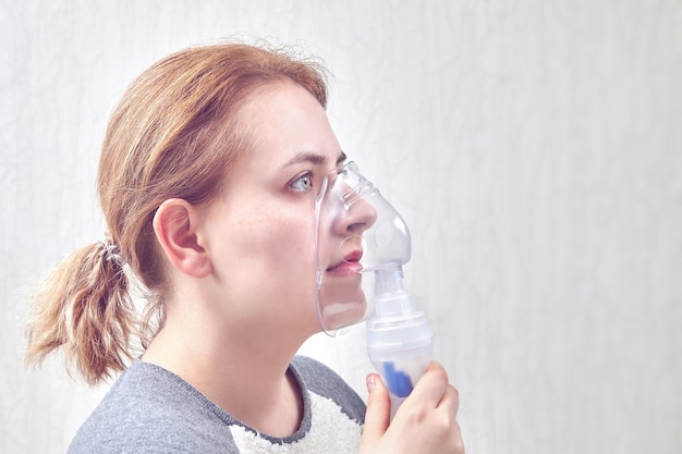 Chica inhala medicina a través del dispositivo para inhalar nebulizar, ayuda a detener el ataque de asma.