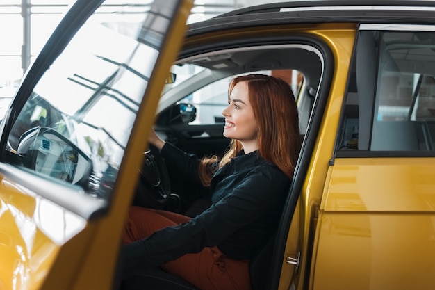 Chica inspecciona un auto nuevo para comprar.