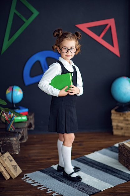 Chica inteligente con libro de texto en la escuela