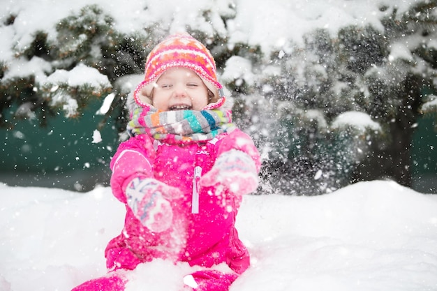 Una chica en invierno cerca de un pino esponjoso con ropa brillante