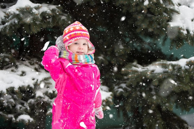 Una chica en invierno cerca de un pino esponjoso con ropa brillante