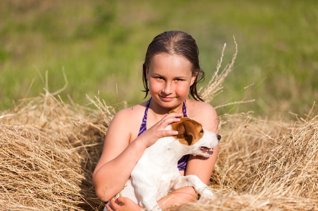 Chica con Jack Russell terrier jugado en heno