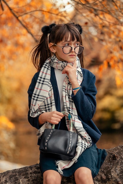 Chica en jaket glassess y falda en el bosque de otoño que parece una chica de anime