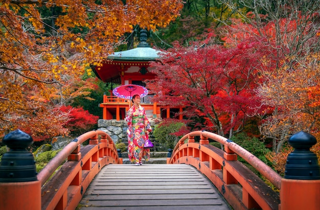 Foto chica japonesa en kimono vestido tradicional caminar en puente rojo en el templo daigoji