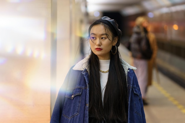 Chica japonesa milenaria con boina de cuero de moda y abrigo espera el tren en el metro