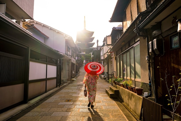 Chica japonesa en Yukata con sombrilla roja en el casco antiguo de Kyoto, Japón