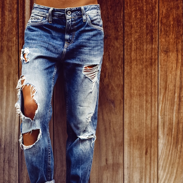 Foto chica en jeans rotos con estilo sobre fondo de madera
