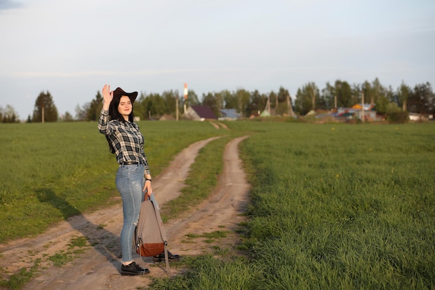 Una chica en jeans y un sombrero viaja el verano en el campo.