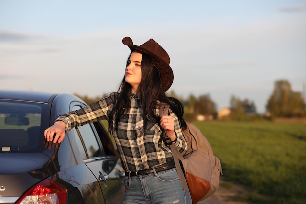 Una chica en jeans y un sombrero viaja el verano en el campo.