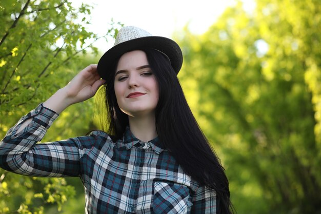 Una chica en jeans y un sombrero viaja el verano en el campo.