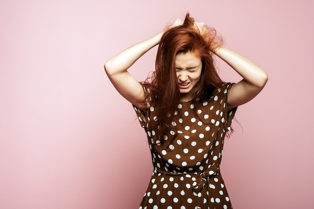 chica jengibre enojada agarrando su cabello