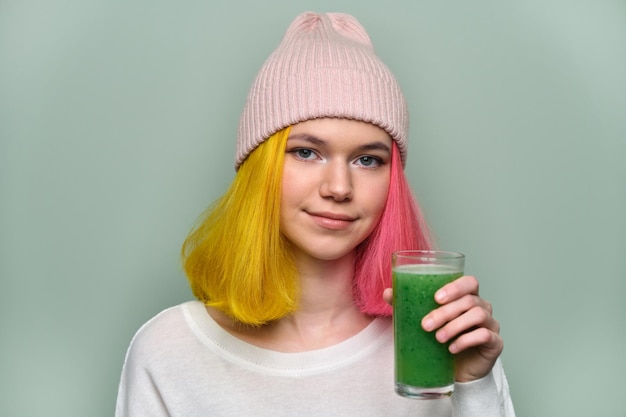 Chica joven adolescente con bebida de batido de verduras verdes, dieta vegana saludable, espacio de copia. Salud, dieta, vegetariana, mujer sobre fondo verde pastel