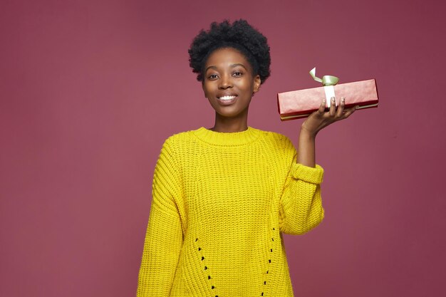 Chica joven afroamericana moderna sosteniendo la caja de regalo actual celebrando la fiesta felicitando con