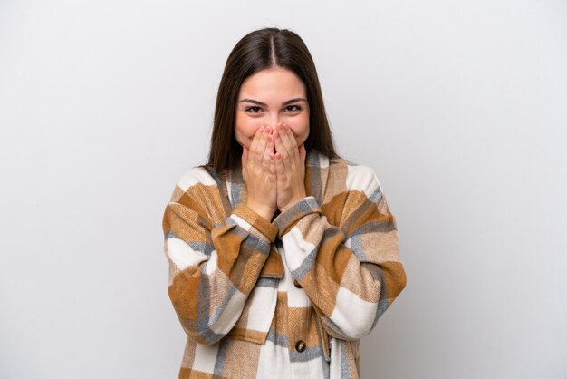 Chica joven aislada sobre fondo blanco feliz y sonriente cubriendo la boca con las manos