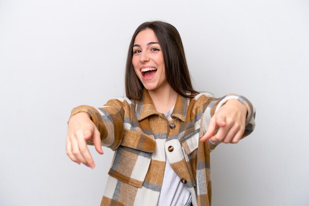 Foto chica joven aislada sobre fondo blanco sorprendida y apuntando al frente