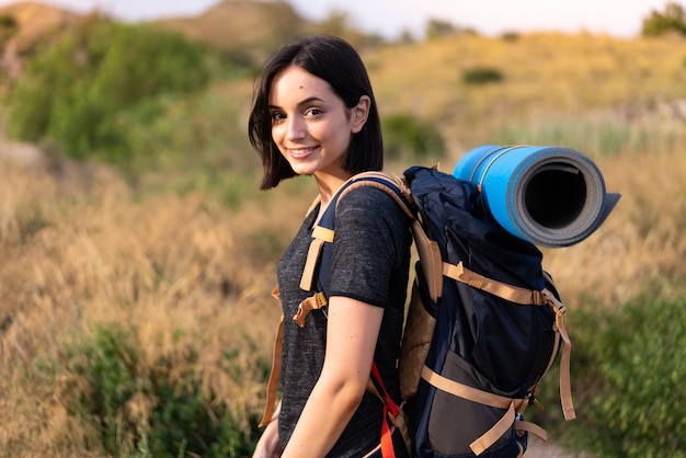 Foto chica joven alpinista con una mochila grande al aire libre