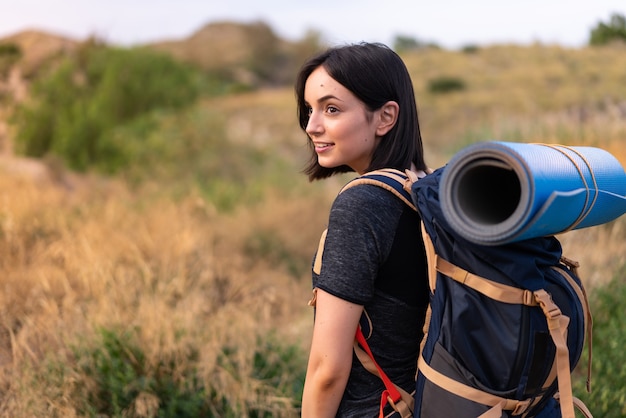 Chica joven alpinista con una mochila grande al aire libre