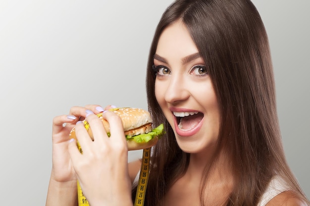 Foto chica joven con apetito come una hamburguesa