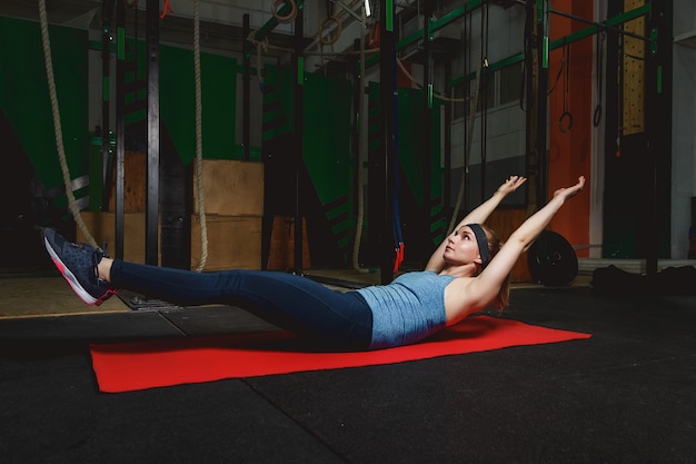 Chica joven de la aptitud en el gimnasio que hace ejercicios con los abdominales. Crossfit