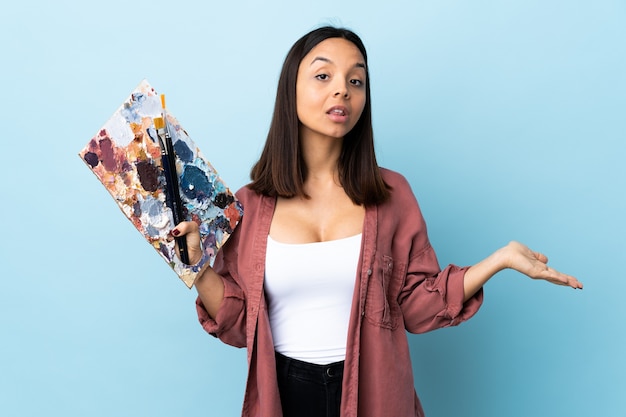 Chica joven artista sosteniendo una paleta con pintura