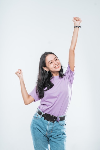 Chica joven asiática sonriendo feliz mientras apretó los puños y levantó las dos manos aisladas