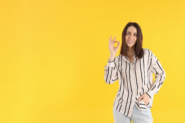 Chica joven atractiva en camisa sobre fondo amarillo