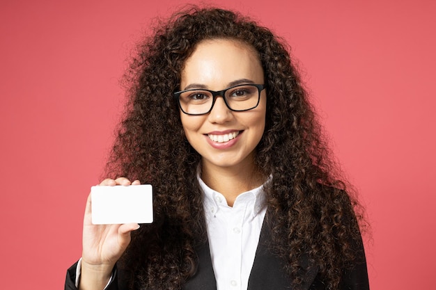 Foto chica joven atractiva con gafas y un traje negro sobre un fondo rojo.