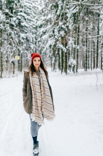 Chica joven atractiva hipster caminando en el bosque de nieve