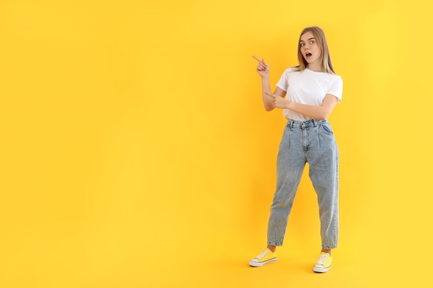 Chica joven atractiva en jeans sobre fondo amarillo