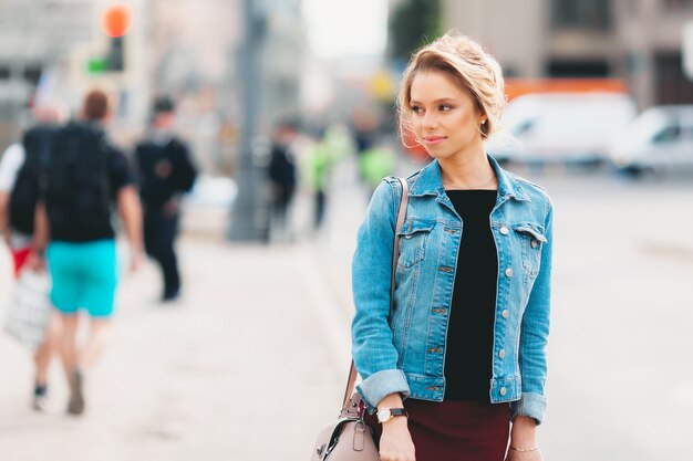 Chica joven atractiva con maquillaje en chaqueta de jeans en la calle en verano