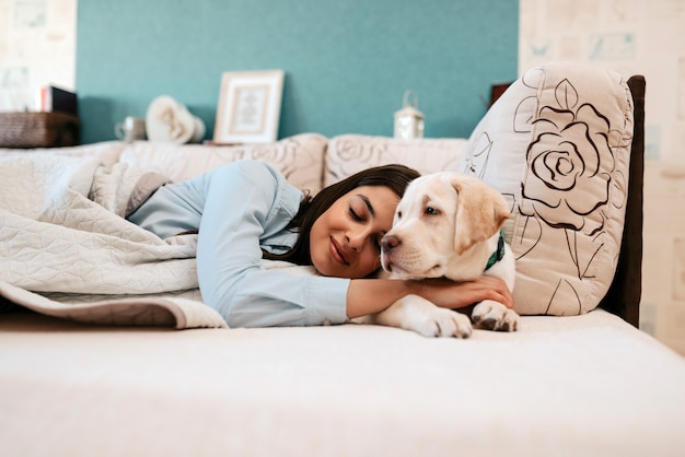 Chica joven atractiva con el perro que pone en una cama.