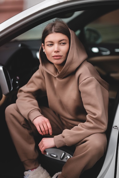 Chica joven atractiva que conduce un coche. La chica sale del coche.