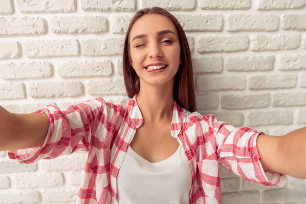 Chica joven atractiva en ropa casual está mirando a cámara