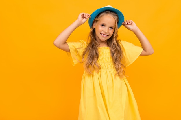 Chica joven atractiva en un sombrero de verano sobre un fondo amarillo