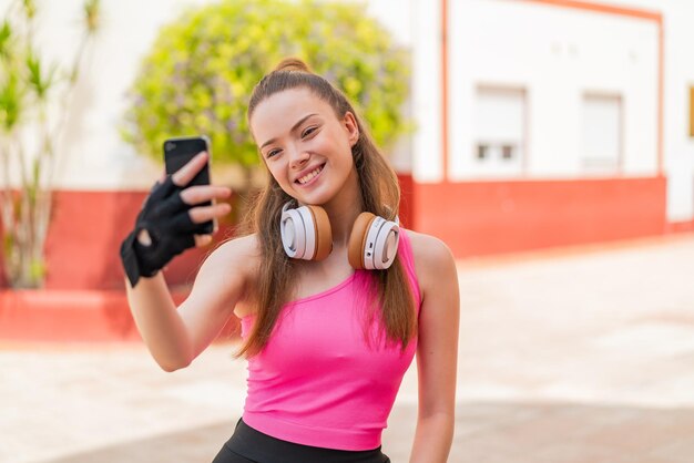 Chica joven bastante deporte al aire libre haciendo un selfie