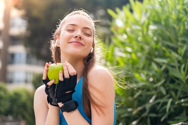 Chica joven bastante deporte al aire libre sosteniendo una manzana