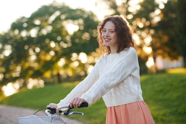 Chica joven con una bicicleta en un parque por la mañana