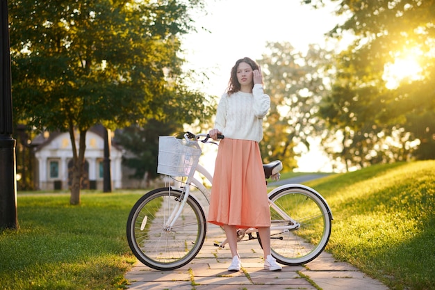 Chica joven con una bicicleta en un parque por la mañana