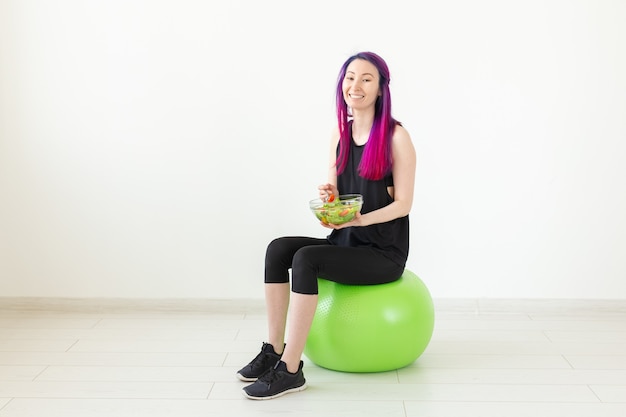 Chica joven blogger de fitness no identificado con ensalada de verduras y cinta métrica. Concepto de estilo de vida deportivo y nutrición adecuada