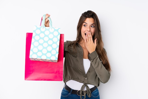 Chica joven con bolsas de compras sobre pared aislada